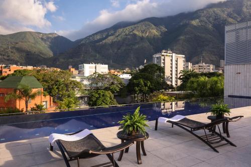 a balcony with chairs and a view of mountains at Cayena-Caracas in Caracas