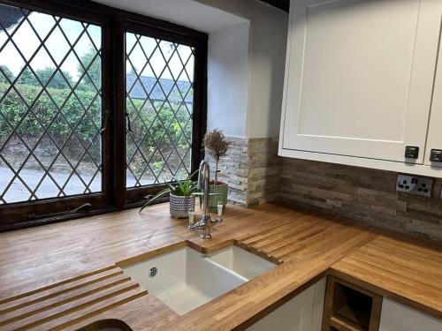 a kitchen counter with a sink and a window at Gorgeous Thatched Cottage in Torquay