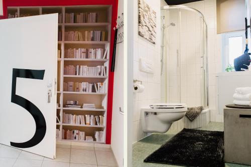 a bathroom with a toilet and a book shelf with books at City Pension in Reichenbach im Vogtland