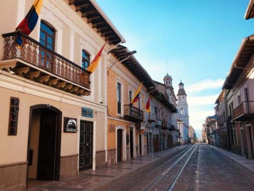 una calle vacía con banderas en edificios y una torre del reloj en Hotel Raymipampa, en Cuenca