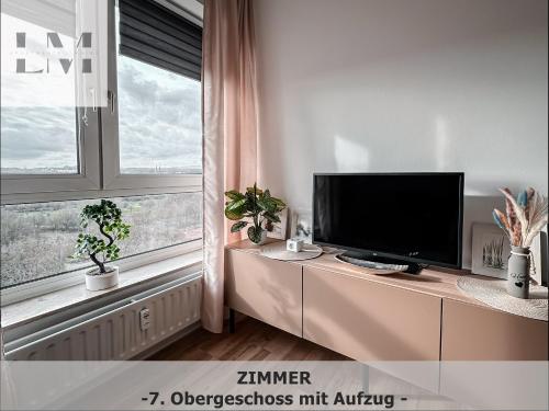 a living room with a tv and a large window at LM-ApartmentsMainz-07 in Mainz