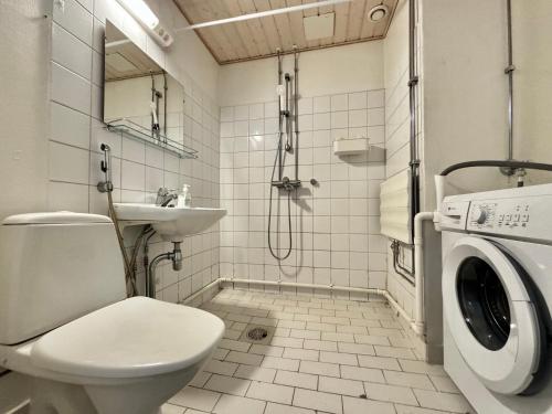 a bathroom with a toilet a sink and a washing machine at Koti+ Outokumpu in Outokumpu