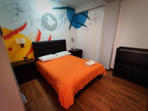 a bedroom with a bed with an orange blanket at Magic Packer Hostel in Cusco