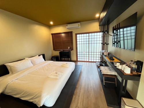 a bedroom with a large white bed and a desk at COZY SHIROI RESORT in Nang Rong