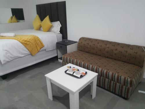 1 dormitorio con cama, sofá y mesa en De Bliss Lodge, en Johannesburgo