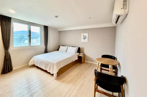 a bedroom with a bed and a table and a window at Hotel Yaja in Geoje