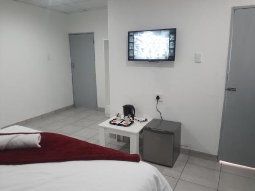 a white room with a bed and a table and a window at De Bliss Lodge in Johannesburg