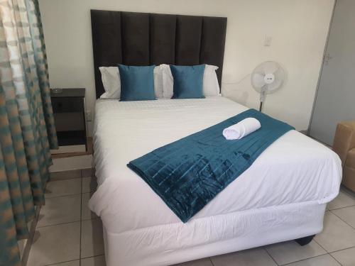 a bedroom with a large white bed with blue pillows at De Bliss Lodge in Johannesburg