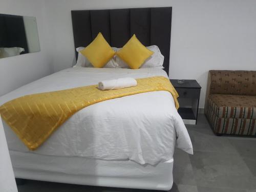 a bed with yellow and white sheets and a yellow blanket at De Bliss Lodge in Johannesburg