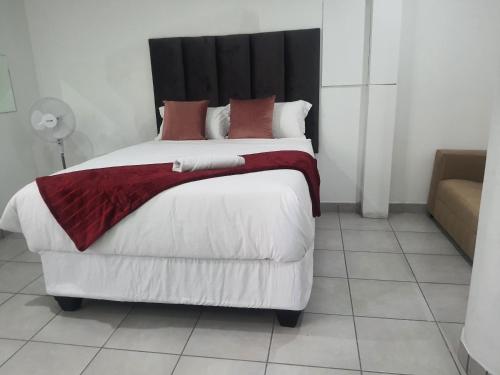 a bedroom with a large bed with red and white pillows at De Bliss Lodge in Johannesburg