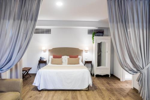 a bedroom with a white bed and blue curtains at Le Petit Boutique Hotel in Santander