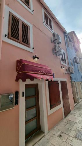 un bâtiment rose avec une porte et un parapluie dans l'établissement Rogdogg apartments center Zadar, à Zadar