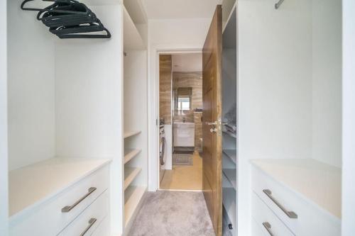 a bathroom with white cabinets and a walk in closet at Amazing One bedroom Penthouse in Wimbledon in London