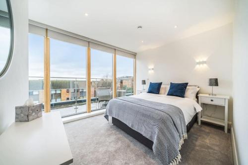 a white bedroom with a bed and a large window at Amazing One bedroom Penthouse in Wimbledon in London