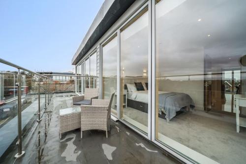 a bedroom with a bed on a balcony with windows at Amazing One bedroom Penthouse in Wimbledon in London