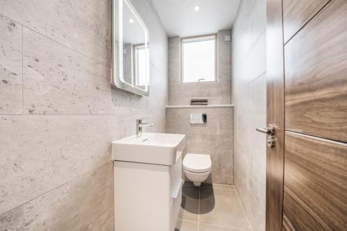 a bathroom with a toilet and a sink and a window at Amazing One bedroom Penthouse in Wimbledon in London