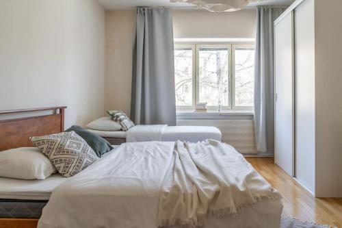 1 dormitorio con 2 camas y ventana en 2-Bedroom, Steps from the Metro!, en Helsinki