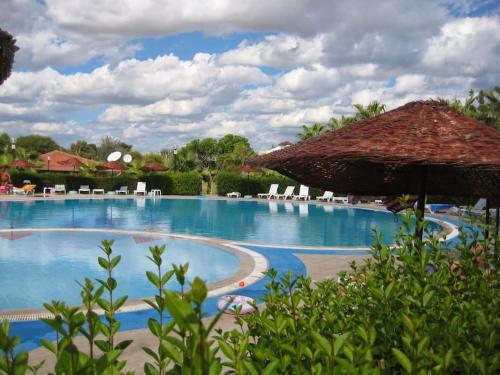 a pool at a resort with chairs and an umbrella at VİLLA KEYF in Side