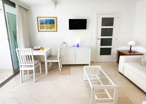 マルベーリャにある1 Bedroom Apartment Second Line Beach- Parque Marbella Buildingの白いリビングルーム(テーブル、ソファ付)