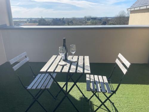 d'une table et de deux chaises avec des verres à vin sur le balcon. dans l'établissement Studio avec terrasse proche de la mer, à Lancieux
