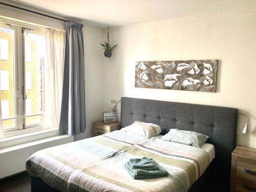ein Schlafzimmer mit einem Bett, einer Decke und einem Fenster in der Unterkunft Nicolette Apartments in Katwijk