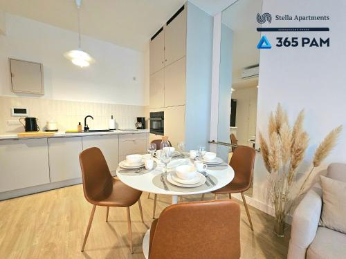 a white dining room table with chairs and a kitchen at Apartament Dobra Aura - 365PAM in Ustronie Morskie