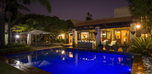 a swimming pool in front of a house at night at Opikopi Guest House in Pretoria