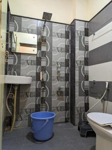 a bathroom with a toilet and a sink and a bucket at Vijayanagara Home Stay in Hampi