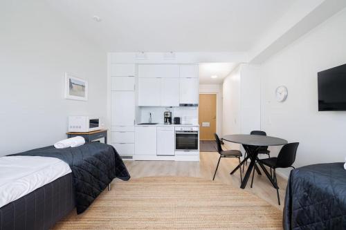 a bedroom with a bed and a table and a kitchen at ULEABO New & Cozy Top Floor Studio in Oulu