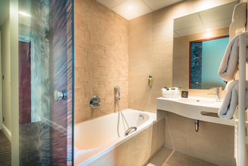 a bathroom with a tub and a sink and a shower at Hôtel France et Chateaubriand in Saint Malo