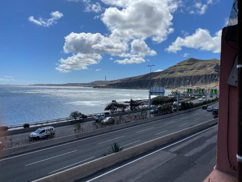 a road with cars driving on it next to the water at la laja 38 in Las Palmas de Gran Canaria