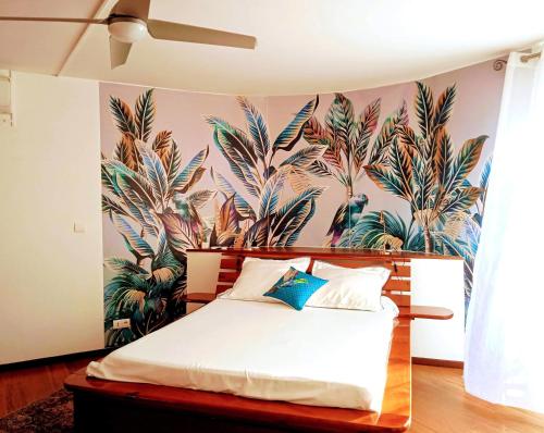 1 dormitorio con 1 cama con un mural de palmeras en Le vol du Cardinal, en Saint-Pierre