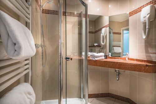 a bathroom with a glass shower and a sink at Hôtel France et Chateaubriand in Saint Malo