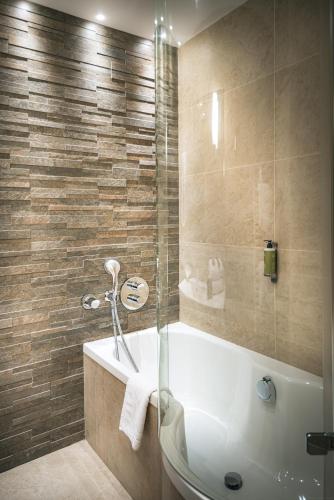 a bathroom with a tub and a glass shower at Hôtel France et Chateaubriand in Saint Malo