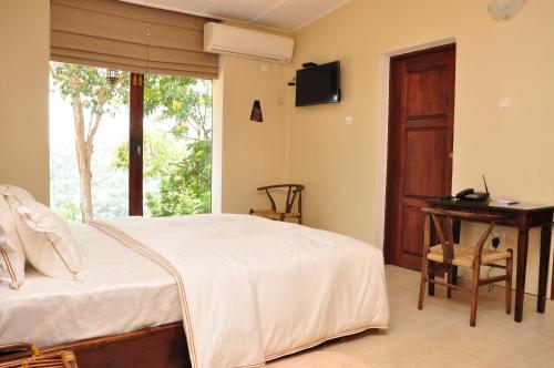 a bedroom with a bed and a desk and a window at The Buena Vista Kandy in Kandy