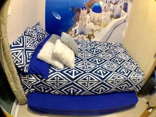 a bed with blue and white pillows in a room at The Grass Residences in Manila