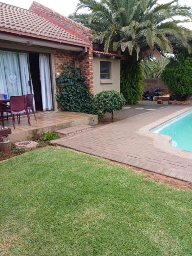 a house with a patio and a swimming pool at Cura Lodge in Bloemfontein