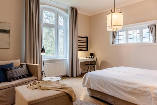 1 dormitorio con cama, sofá y ventana en Aarskogs Boutique Hotel, en Glücksburg