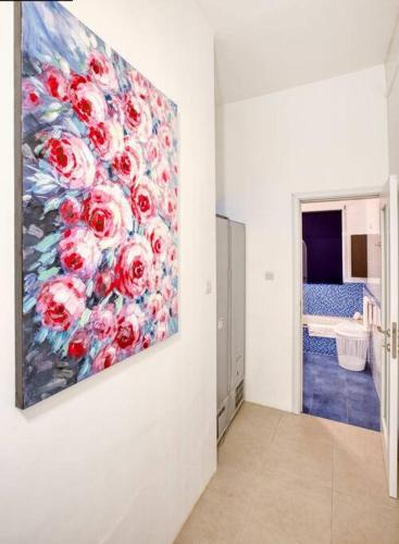 a painting of red roses is hanging on a wall at Bright & Airy St. Julian's flat in Il-Gżira