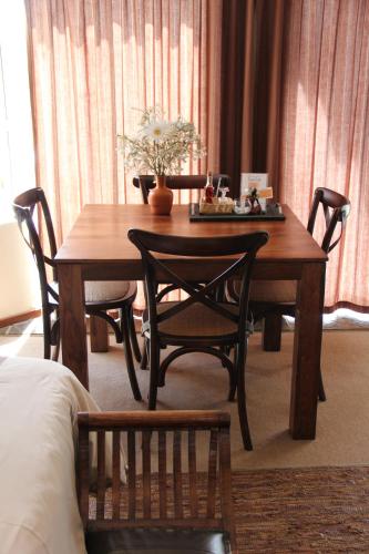 a wooden table with chairs and a table with flowers on it at Glenda's Guest Suites in Midrand