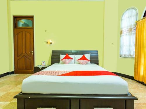 a bedroom with a large bed with red pillows at Senaz Guesthouse in Mataram