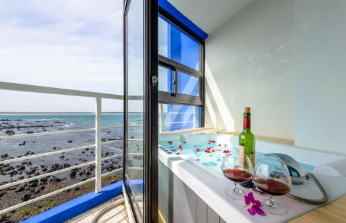 a room with a view of the beach and two glasses of wine at On The Sea Pension in Jeju
