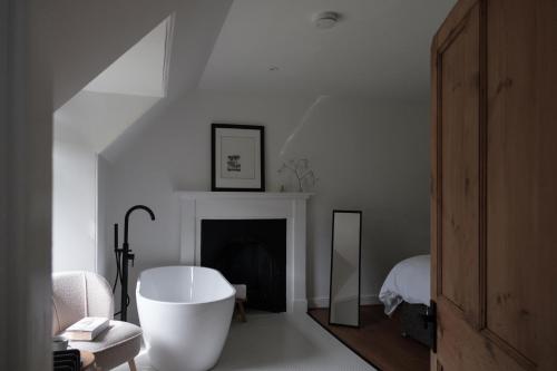 a white room with a bath tub and a fireplace at Ballintaggart Farmhouse in Logierait