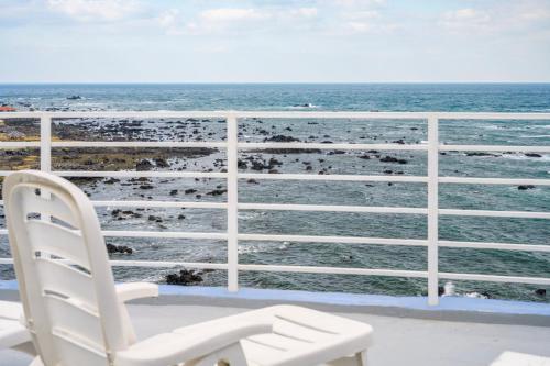 a white chair sitting on a balcony looking at the ocean at On The Sea Pension in Jeju