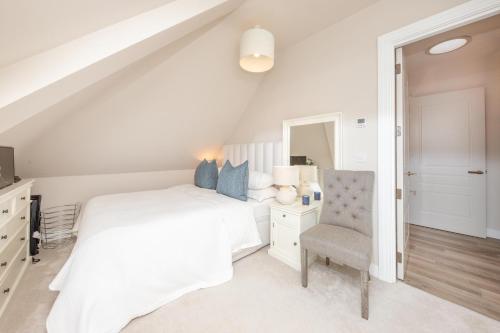 una camera bianca con un letto e una sedia di Luxury 2 Bed Apartment - 28 mins train to London a Addlestone