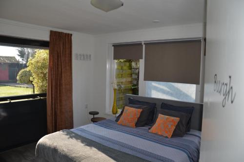 een slaapkamer met een bed met oranje kussens en een raam bij B&B Onder de Molen in Burgh Haamstede