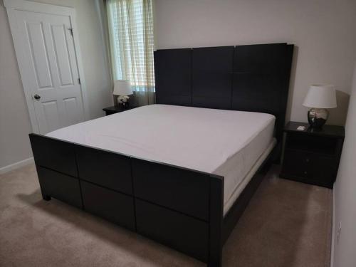 een slaapkamer met een groot bed met een zwart hoofdeinde bij One bedroom apartment fully furnished with private entrance in Puyallup