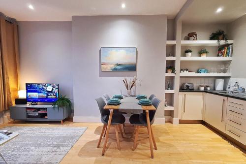 a kitchen with a table with chairs and a television at Central London 1 bedroom flat in Kensington in London