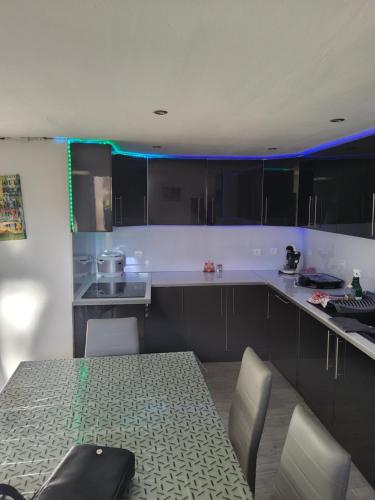 cocina con mesa, sillas y luz azul en Adorable appartement, en Pézenas
