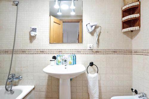 een witte badkamer met een wastafel en een spiegel bij Apartamento Coto 109 in Chiclana de la Frontera
